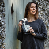 Woman holding a black and white cowhide travel wallet and clutch, highlighting its chic style and functional design for a fashionable look