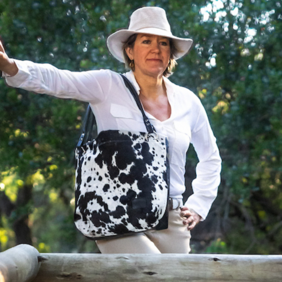 Woman wearing a black and white cowhide slouch bag, styled with a western boho outfit, showcasing a chic and effortless vibe