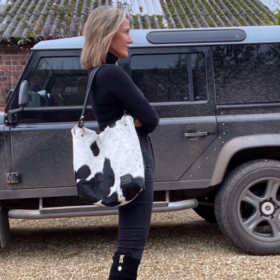 Woman wearing a black and white cowhide slouch bag, styled with a western boho outfit, showcasing a chic and effortless vibe