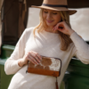 Woman holding a brown and white cowhide travel wallet