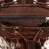Close-up of the interior of a brown cowhide bucket bag, showing the zip pocket and leather drawstring closure