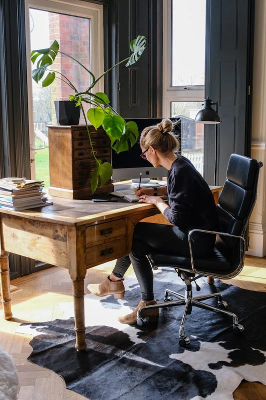 Women at desk in home office with Black and White cowhide rug underneath 