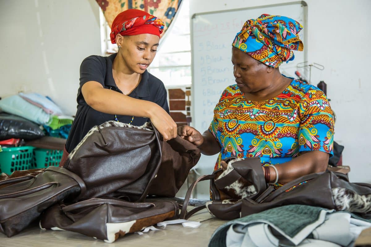 Zulu ladies in workshop with sewing machine and cowhide hand bag ethically-made, artisan-made, sustainable interiors, cowhide bags, cowhide rugs, sustainable, slow fashion,