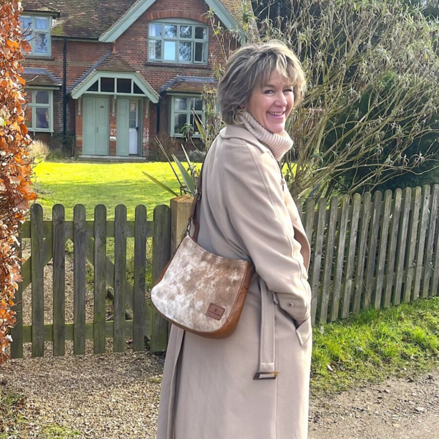 Woman wearing a brown and white cowhide saddle bag, showcasing the bag's unique cowhide pattern and adjustable strap