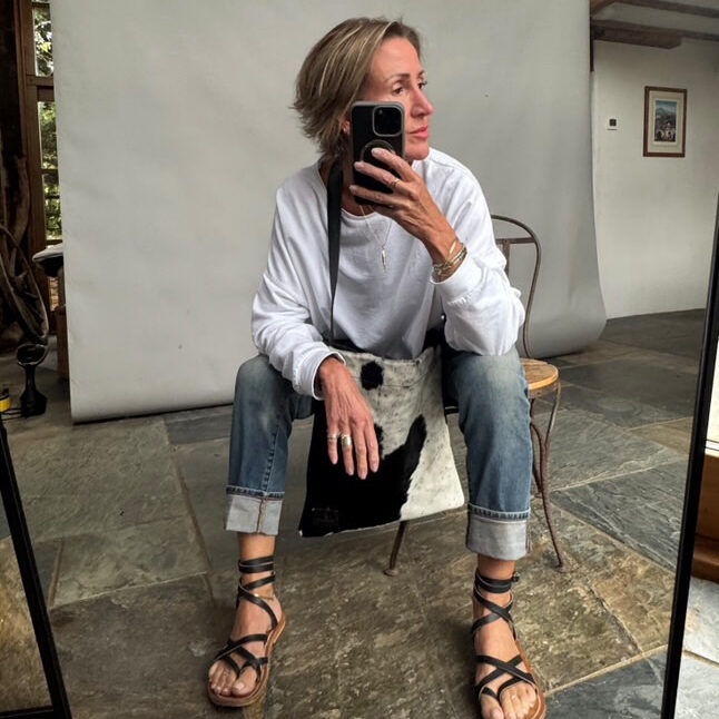 Helen takes a mirror selfie wearing the cowhide messenger bag in black and white