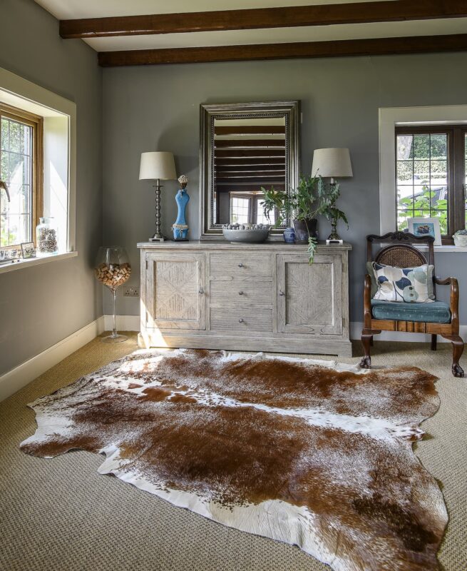 A brown and white cowhide rug in a stylish country style living room