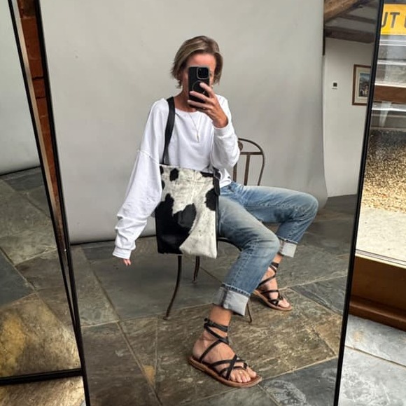 Helen poses with black and white cowhide messenger bag